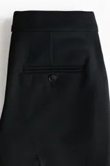Pantalón tobillero negro de corte bootcut, con raya marcada adelante y atrás. Cuenta con cintura estándar con elástico oculto, cierre con pretina prolongada y botones, bolsillos al bies y bolsillo trasero ribeteado.