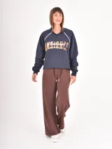 Pantalon de estilo deportivo en color gris oscuro, confeccionado en tejido de punto suave. Presenta un corte recto y holgado, cintura elástica con cordón ajustable y costuras verticales decorativas en el frente.