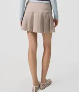 Short pollera de tiro alto en color beige, con diseño de sastrería, tablas delanteras y ruedo asimétrico.