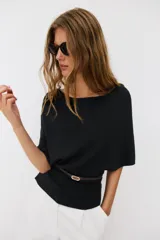 Top de punto color beige con cuello barco y mangas cortas anchas tipo murciélago. Cuenta con cintura entallada con ribete elástico y un cinturón fino de cuero sintético marrón con hebilla metálica dorada.
