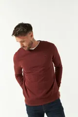 Sweater de punto con escote en V, manga larga y puños acanalados. Presenta un diseño clásico con logo bordado en el pecho.