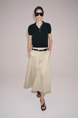 Top negro de punto fino con cuello polo, manga corta, cierre frontal de botones y un bolsillo de parche en el pecho.