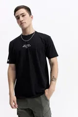 Remera de manga corta color beige con cuello redondo y estampado grande en la espalda. El estampado incluye un gráfico abstracto en tonos naranjas y morados, la palabra "Persistence" en vertical y un texto motivacional debajo.