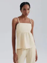 Blusa color beige de lino con breteles finos ajustables y detalle de botones decorativos.