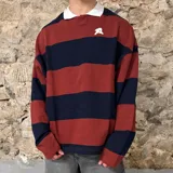 Buzo tipo polo de corte oversize, con diseño de rayas horizontales anchas en color bordó y azul marino. Presenta cuello polo blanco y un pequeño logo bordado en el pecho.