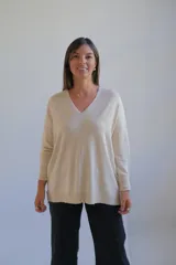 Sweater de punto color crudo, con escote en V, manga larga y diseño holgado con costura central vertical.