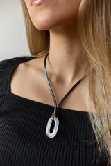 Collar con tiento de cuero negro y dije ovalado de piedra natural color rosa pálido.