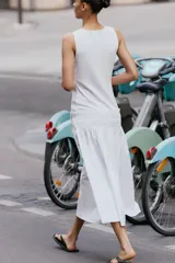 Vestido midi de color blanco con cuello redondo y manga sisa, confeccionado con un diseño combinado que presenta un cuerpo de tejido liso y una falda vaporosa con cintura elástica fruncida y cordón ajustable.