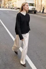 Jersey de punto negro, con cuello en V (pico) y manga larga, acabado en rib en puños, cuello y bajo.