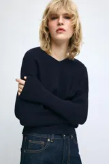 Jersey de punto color mostaza con escote en pico y manga larga con puños ajustados.