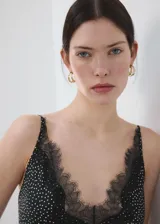 Vestido midi de estilo lencero color negro con estampado de lunares blancos, escote en V con detalle de encaje negro, tirantes finos y diseño entallado.