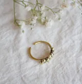 Anillo dorado con diseño de racimo de pequeñas esferas.