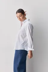 Camisa de algodón blanca, de calce relajado, con cuello clásico, mangas largas y cierre frontal con botones.