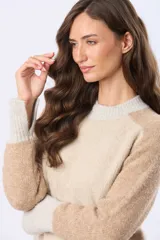 Buzo tejido de punto con diseño de bloques de color en tonos rosa, beige y gris. Presenta cuello redondo, mangas largas y puños acanalados.