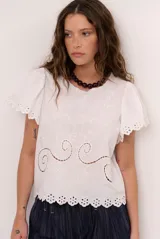 Blusa blanca de manga corta con detalles de bordados y perforaciones, cuello redondo y diseño holgado.