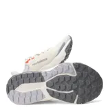 Championes New Balance Nitrel, diseñados para trail running y uso urbano, de color beige con detalles en gris y toques de naranja. Presentan capellada de malla transpirable con refuerzos, entresuela acolchada y suela con tracción especializada.