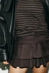 Falda pantalón de tiro medio color marrón oscuro, con detalle de volantes y cierre lateral con cremallera oculta.