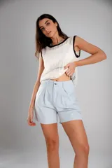 Short blanco de tiro alto con pliegues frontales y cierre de botón metálico.