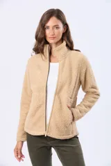 Campera beige de poliéster con textura sherpa, cierre frontal con cremallera marrón y bolsillos laterales.