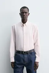 Camisa de corte regular fit confeccionada en tejido de algodón con diseño de rayas finas. Presenta cuello solapa, cierre frontal de botones y manga larga con puños abotonados.