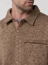 Chaqueta de polar para hombre en color marrón con textura jaspeada. Presenta un diseño tipo camisa con cuello, cierre frontal de botones a presión, un bolsillo horizontal en el pecho y bolsillos laterales abiertos.