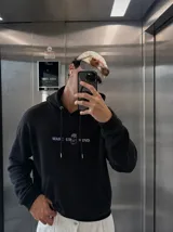 Canguro negro con capucha y bolsillo tipo canguro, confeccionado con felpa suave premium. En la espalda presenta una estampa temática con un esqueleto dentro de un ataúd y las leyendas "Wake Up" y "Kaboa Industries".