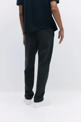 Pantalón tipo jogger de punto en tono gris oscuro, con cintura elástica y cordón ajustable. Presenta un pliegue cosido en el frente de cada pierna, bolsillos laterales y un bolsillo insertado trasero.