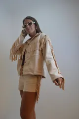 Campera color beige de gamuza sintética con flecos en mangas, espalda y ruedo.