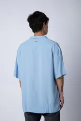 Camisa de manga corta con cuello cubano, confeccionada en fibrana premium. Presenta un corte oversize y cierre frontal con botones al tono.