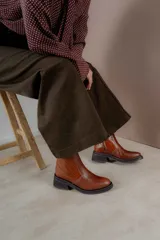 Bota corta de cuero marrón con panel trasero de gamuza en tono más oscuro, suela de goma negra y taco cuadrado bajo.