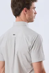 Camisa de manga corta de algodón en color celeste con microdiseño geométrico a cuadros, cuello camisero y bolsillo frontal con logo bordado.