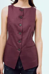 Top estilo chaleco sin mangas, de color bordó, con cuello redondo y cierre frontal con botones oscuros. Presenta bolsillos ojal simulados en la parte inferior del frente.