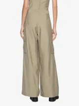 Pantalón color beige, de tiro medio, corte recto y largo hasta las rodillas. Presenta dos solapas que sobresalen de la pretina y dos bolsillos cargo a los costados de las piernas.