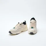 Zapatillas deportivas de estilo urbano confeccionadas en malla y material sintético. Presentan una combinación de colores en crema, negro y verde, con suela robusta y diseño ergonómico.