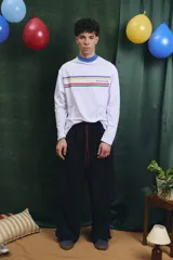 Remera de manga larga blanca con cuello alto en color azul. Presenta franjas horizontales de colores en el pecho y el logo de la marca estampado.