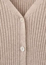 Cardigan de punto fino color beige, entallado, con cuello en V, manga larga acampanada, bajo con volante y cierre frontal con botones.