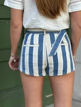 Short de jean a rayas verticales azules y blancas, con cintura alta y cinturón de tela con hebilla redonda.