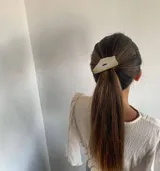 Accesorio para el pelo tipo colita, color crema, con forma irregular y abertura central.