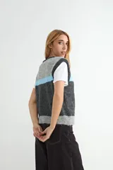 Chaleco tejido de punto con diseño de bloques de color en tonos marrón, naranja y crema. Presenta cuello redondo, cierre frontal con botones y terminaciones acanaladas en el ruedo y sisas.