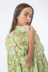Vestido corto verde con estampado floral, cuello alto, mangas cortas abullonadas y corte holgado.