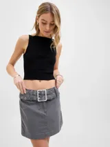 Minifalda gris de tiro medio, confeccionada en denim, con diseño de corte recto y presillas con cinturón ancho decorado con ojales metálicos y hebilla rectangular.