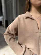 Buzo de punto color rosa, con cuello polo abierto y mangas largas de diseño holgado.