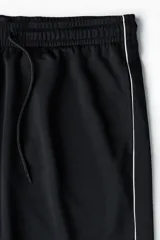 Short de futbol negro de malla, con cintura elástica y cordón ajustable. Cuenta con ribetes blancos en los laterales, bolsillos y el logo de Lotto estampado en blanco en la pierna izquierda.
