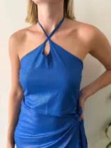 Conjunto de dos piezas color azul brillante, compuesto por un top halter con breteles finos y lazo regulable en el contorno, y una falda corta cruzada regulable.