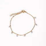 Pulsera dorada de cadena fina con cierre de mosquetón y extensión para ajustar el largo. Tiene dijes colgantes de circonitas engarzadas.