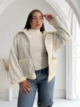 Campera corta color crudo de ecocuero con interior de corderito, cierre frontal con cremallera y bolsillos laterales.