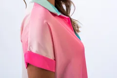 Vestido camisero corto, con diseño color block en rosa y celeste. Tiene cuello camisero, mangas cortas con puños y cierre frontal con botones.