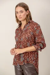 Camisa de manga larga con estampado de leopardo, cuello clásico y cierre frontal de botones. Presenta un corte holgado y puños abotonados.