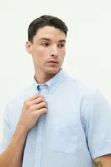 Camisa de manga corta confeccionada en una mezcla de lino y algodón, con cuello clásico, cierre frontal de botones y bolsillo en el pecho con logo bordado.