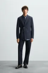 Blazer regular fit color azul marino, confeccionada en tejido con lana. Presenta cuello con solapas de pico, manga larga con puño abotonado, bolsillos de vivo en el pecho y de plastrón en la cadera. Incluye un bolsillo interior y aberturas en la espalda. El cierre es frontal con botonadura cruzada.